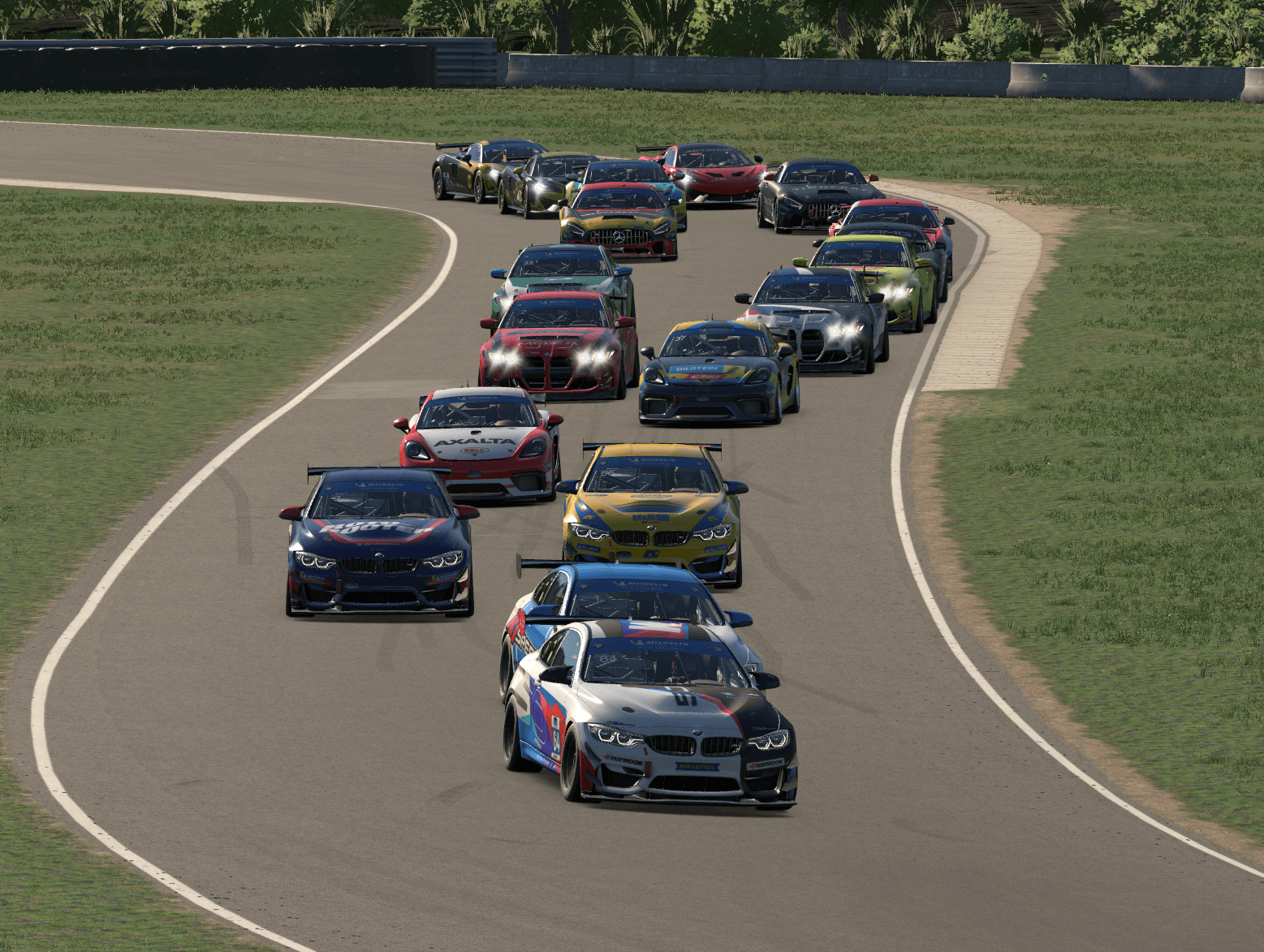 A full field of GT4 cars racing through a sweeping corner